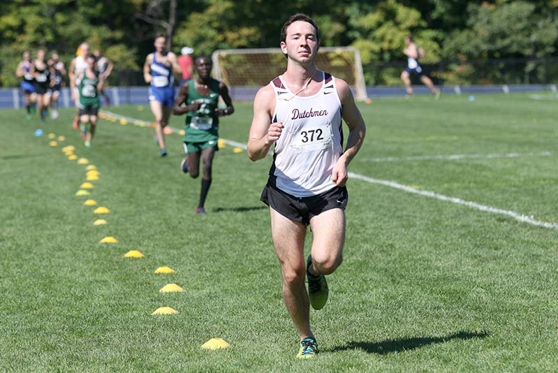  A runner from the men's cross-country team sprints towards the finish line, determined and focused.