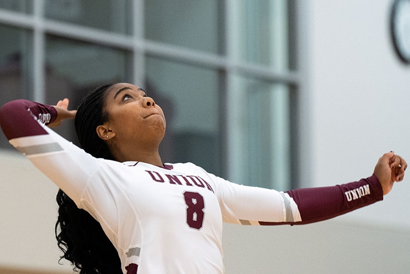 A volleyball player on the women's team gazes upward in anticipation of the ball heading her way.