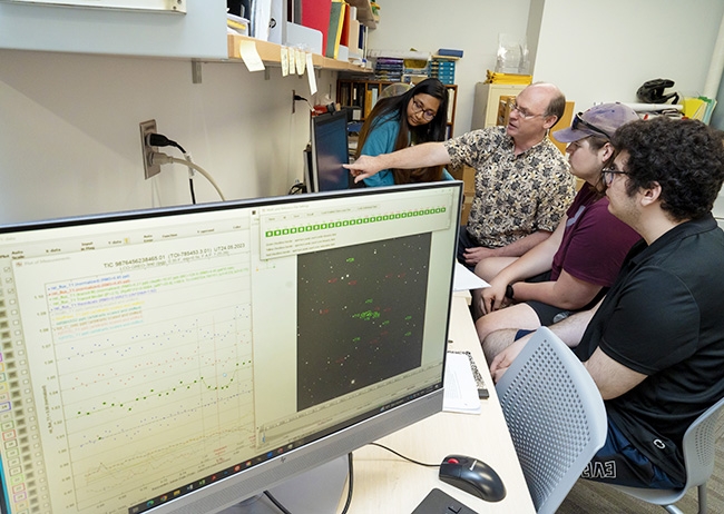 Francis Wilkin, a senior lecturer in the Department of Physics and Astronomy gestures at a screen as a number of students look on.