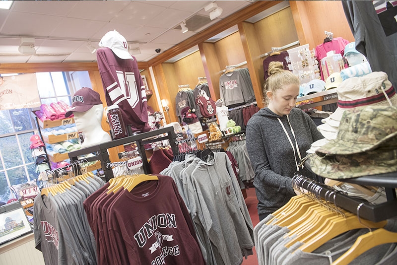 A student browsing sports apparel for sale in the Union College Bookstore.