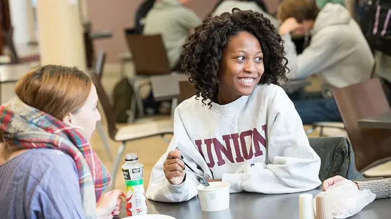 A smiling student at a table in Dutch Hollow having some soup