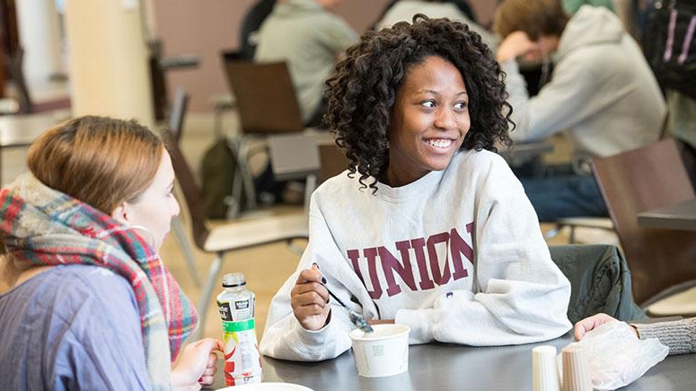 A smiling student at a table in Dutch Hollow having some soup