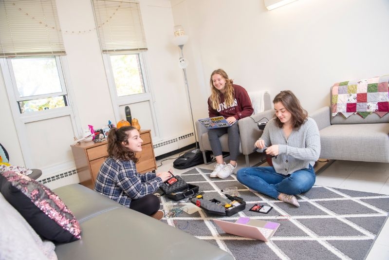 three students sitting on the floor in their res hall working on engineering projects