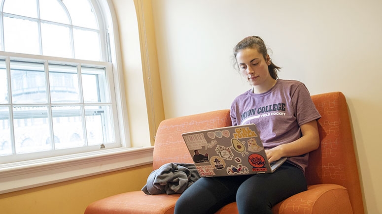A student seated, focused on their laptop, in one of the Karp loung