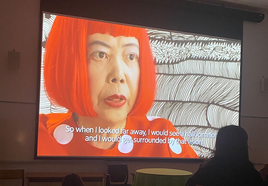 A student watches a video presentation projected against a wall