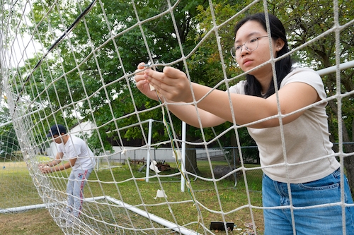 On a hot, sticky morning, Zaid Fafouri ’26 and Austin Gregory ’25 took turns kicking soccer balls into a net at Garis Field. Over the course of two hours, they would repeat this routine hundreds of times. Thud. Thud. Thud. Crouched safely behind the net, Nguyen Ho ’26 collected data into her laptop from a series of sensors attached to the netting. Each shot generates 1,800 pieces of data. After the final kick, they will retreat to a lab to analyze the data