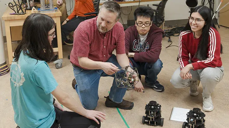 John Rieffel, professor of computer science and department chair,  works with students on tensegrity robots in the CROCHET Lab.  Rieffel’s research uses AI to optimize movements of these “soft  robots”—composed of rigid struts and springs—that have potential  applications in search-and-rescue, space exploration and surgery.  