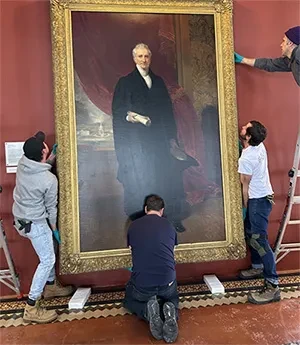 Workers carefully prepare to return a historic portrait of Eliphalet Nott, Union's longtime president, to its pictorial space at the back of the Nott Memorial. The painting had been removed in March 2022 to be restored&nbsp;at the Williamstown Art Conservation Center.