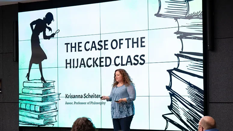 A professor stands at the front of a lecture hall, gesturing while presenting a slide titled "The Case of the Hijacked Class."