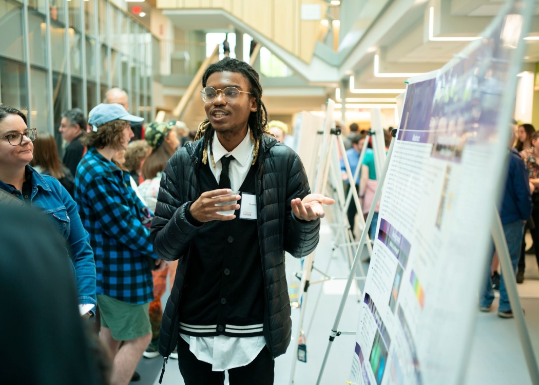 Student presenting original research in front of a poster