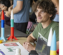 Students sit at a table encouraging passersby to join the college’s rocket club.