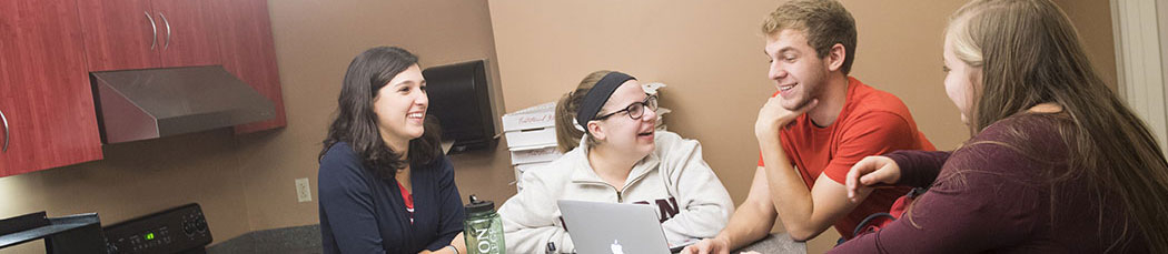 Students gathered around a table enjoy some conversation.