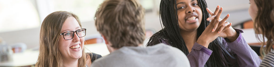 Students eat lunch in Reamer Dining Hall, gathered around a table laughing and enjoying one another’s company and good food.