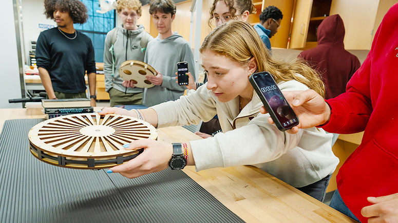 A student carefully places a disk above a platform during a magnetic levitation experiment.