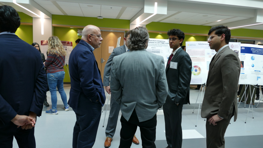 A faculty member, a guest and students conversating at the 1st annual Combined Degree Student Research symposium