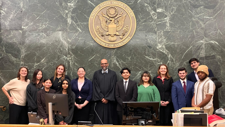 11 people standing at the US Supreme Court of DC in front of the court room, with a judge in the center