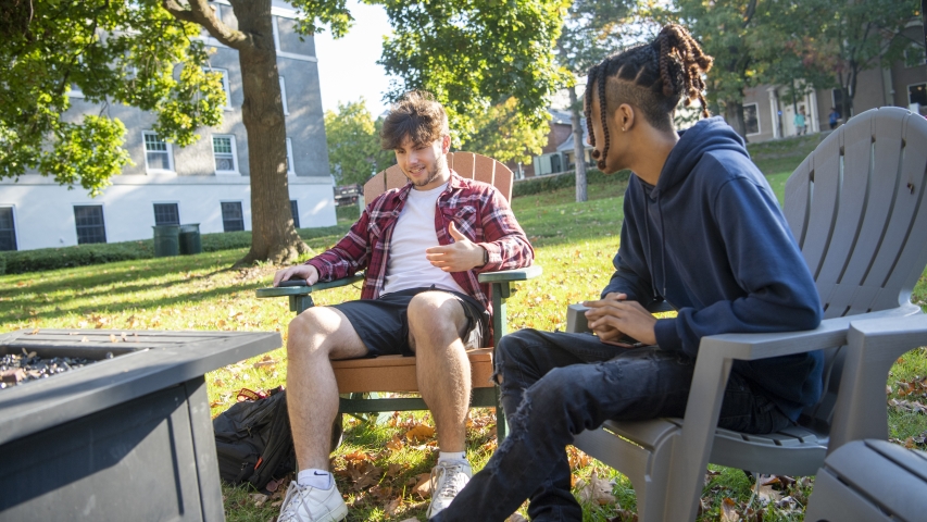 two students sitting outside of richmond house next to a fire pit