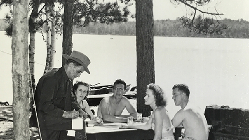 A forest ranger writes a ticket to unamused group enjoying a warm summer’s day.