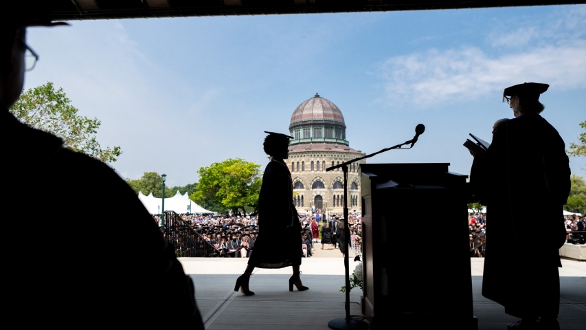 A student in Silhouette walks across the stage to accept her diploma.