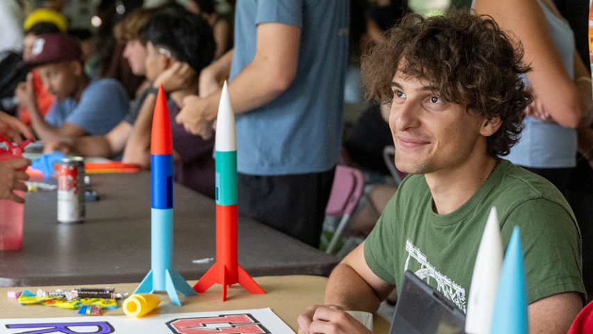 Students seated at a table with model rockets