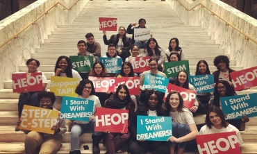 Students and staff with signs sitting on the stairs at the State Capitol in Albany