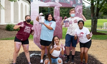 Student painters pose in front of the new Block U sculpture