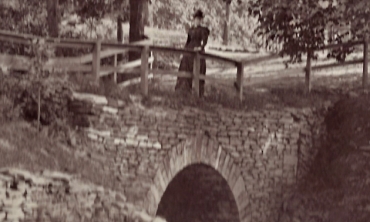 An unidentified woman walks across a bridge at Jackson Gardens, date unknown.