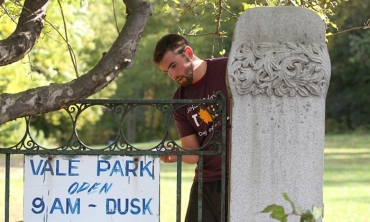 A student volunteer painting a fence in Vale Park, Schenectady