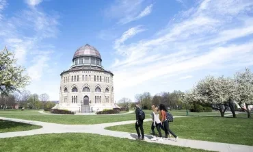 Students walking across campus with the Nott Memorial in the background
