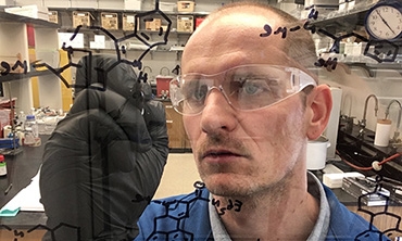 Chemist and neuroscientist David Olson photographed drawing diagrams upon a glass board