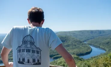 A student perched on a mountain top looking down at a winding river