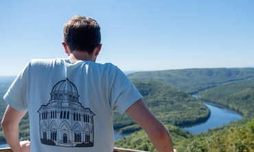 A student perched on a mountain top looking down at a winding river