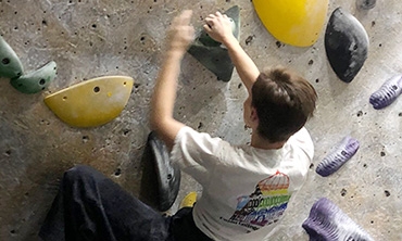 Sarina Kuersteiner clinging to an indoor rockwall