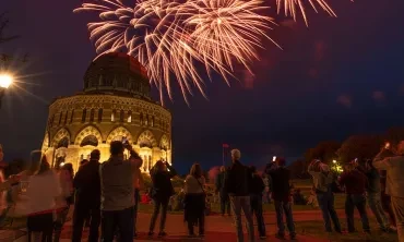 A crowd looks at fireworks exploding above the Nott Memorial.