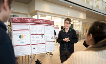 A student presents his research in front of a poster during the annual Steinmetz Research Symposium at Union College